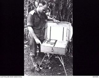 NADZAB AREA, NEW GUINEA. 1943-09-20. INTELLIGENCE OFFICERS BOX FOR USE IN JUNGLE WARFARE DESIGNED BY THE 7TH AUSTRALIAN DIVISION INTELLIGENCE OFFICER. DEMONSTRATING THE BOX IS SX8690 CAPTAIN A. H. ..