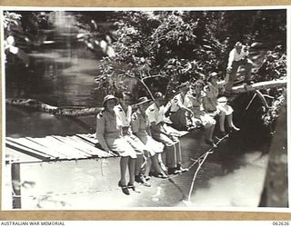 KOITAKI, NEW GUINEA. 1944-01-02. PATIENTS OF THE 47TH AUSTRALIAN CAMP HOSPITAL IN THE GROUNDS OF THE HOSPITAL WITH THE MATRON AND SOME OF THE STAFF SITTING ON THE SUSPENSION BRIDGE OVER THE EWORGO ..