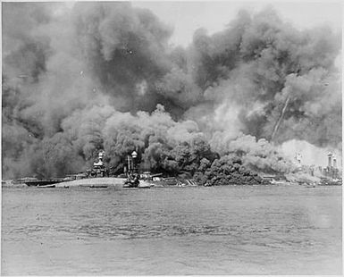 Naval photograph documenting the Japanese attack on Pearl Harbor, Hawaii which initiated US participation in World War II. Navy's caption: "Battleship Row" is a mass of flames and smoke, with USS OKLAHOMA in the foreground, after the Japanese attack on Pearl Harbor on Dec. 7, 1941.