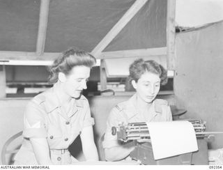 LAE, NEW GUINEA, 1945-05-23. SERGEANT M.F. SHEWAN (1), DICTATING NOTES TO SERGEANT B.M. DANIELS (2), AT 4 ADVANCED ORDNANCE DEPOT. THEY ARE AMONG AUSTRALIAN WOMEN'S ARMY SERVICE PERSONNEL AT LAE TO ..