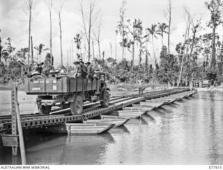 BOUGAINVILLE ISLAND. 1944-12-06. TRUCKS CARRYING MEMBERS OF THE 15TH INFANTRY BATTALION CROSS THE PONTOON BRIDGE BUILT BY THE TROOPS OF THE 5TH FIELD COMPANY, OVER THE REINI RIVER DURING THEIR ..