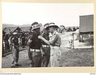 WEWAK POINT, NEW GUINEA. 1945-10-02. LIEUTENANT COLONEL R.R. GORDON, COMMANDING OFFICER 2/3 MACHINE-GUN BATTALION (3) PINNING THE MILITARY MEDAL RIBBON ON NX80787 SERGEANT E. HAYLETT A MEMBER OF 12 ..