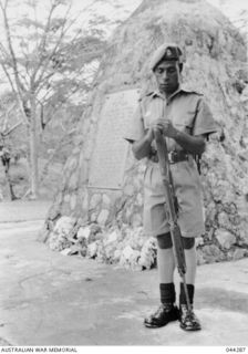 Kokoda, Papua-New Guinea. A Papuan soldier standing at arms reversed next to the Memorial at Kokoda erected to commemorate the exploits of the Australian forces in late 1942