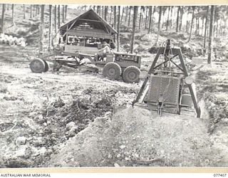 PALMALMAL PLANTATION, NEW BRITAIN. 1944-11-29. PERSONNEL OF THE 2/3RD RAILWAY CONSTRUCTION COMPANY, 48TH DEPUTY COMMANDER ROYAL ENGINEERS (WORKS) USING A BULLDOZER TO DIG A DRAINAGE CULVERT ACROSS ..