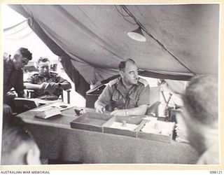 CAPE WOM, NEW GUINEA. 1945-10-20. LIEUTENANT COLONEL W.H. MENCE, CORPS OF AUSTRALIAN ELECTRICAL AND MECHANICAL ENGINEERS, 6 DIVISION IN CONFERENCE WITH OFFICERS COMMANDING CORPS OF AUSTRALIAN ..