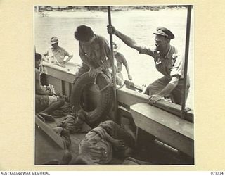 WASU, PAPUA, 1944-03-25. WX8342 LIEUTENANT H. E. READ (1), PAPUAN INFANTRY BATTALION, BOARDING AN AUSTRALIAN ARMY WATER TRANSPORT CRAFT WITH A JAPANESE PRISONER OF WAR