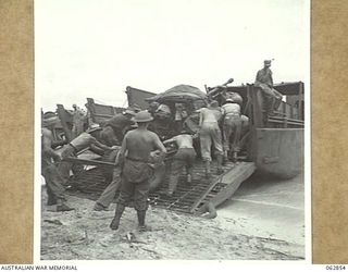 KELANOA HARBOUR, NEW GUINEA. 1944-01-13. MEMBERS OF THE 2/3RD LIGHT ANTI-AIRCRAFT REGIMENT HAULING ONE OF THEIR BOFORS 40MM ANTI AIRCRAFT GUNS ABOARD AN LCM (LANDING CRAFT MECHANISED) FOR TRANSPORT ..