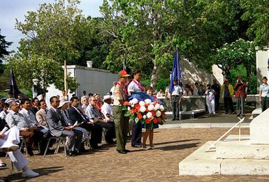 A Boy Scout and a Girl Scout carry a wreath to the base of a monument during the Memorial Day observance at the National Memorial Cemetery of the Pacific, which is also known as the Punchbowl.