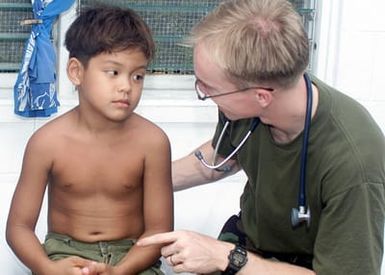 Navy Lieutenant Adam Pacal, a flight surgeon from HMH-463, gives advice to patient Timothy Jutim in Peleliu during a community relations project during Exercise KOA THUNDER 2001. KOA THUNDER is an exercise involving elements of 1ST Marine Air Wing (MAW), and 3rd Marine Division, where Marines conduct an Operational Readiness Exercise (ORE). The Aviation Support Element (ASE) from Kaneohe Bay, Hawaii, will be tested on command and control of several different missions, to include Tactical Recovery of Aircraft and Personal (TRAP), airfield seizures, and a Noncombatant Evacuation Operation (NEO)