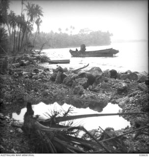 MILNE BAY, PAPUA. 1942-09. ONE OF THE BARGES, USED BY THE JAPANESE IN THEIR UNSUCCESSFUL ATTEMPT TO LAND AT MILNE BAY, GROUNDED ON THE FORESHORE AND WRECKAGE OF JAPANESE EQUIPMENT ON BEACH. NOTE ..