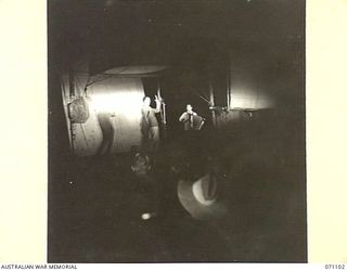 KILIGIA, NEW GUINEA, 1944-03-14. A NIGHT PERFORMANCE BY THE 3RD ARMOURED DIVISION CONCERT PARTY, LIT BY JEEP HEADLAMPS, ON AN IMPROVISED STAGE ERECTED BY THE 5TH AUSTRALIAN DIVISION. A TENT FLY ..