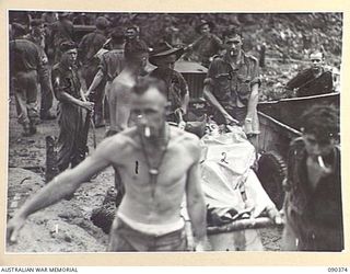BOUGAINVILLE. 1945-04-06. PTE MULCAHY, A COMPANY, 25 INFANTRY BATTALION (2), BEING LIFTED FROM A JEEP AT BATTALION HQ FOR TREATMENT AT THE REGIMENTAL AIR POST. HE WAS WOUNDED IN THE UNSUCCESSFUL ..