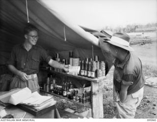 CAPE WOM, WEWAK AREA, NEW GUINEA. 1945-08-31. CORPORAL W.J. BROSCHE (2), BUYING GOODS AT THE UNIT CANTEEN, HEADQUARTERS ROYAL AUSTRALIAN ENGINEERS 6 DIVISION FROM SAPPER V. THOMAS (1)