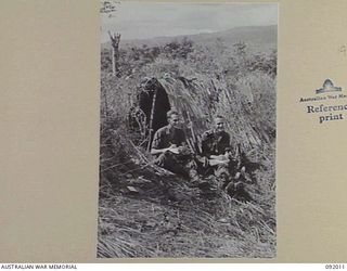 WEWAK POINT, NEW GUINEA, 1945-05-12. PRIVATE W.E. DUNN (1) AND CORPORAL J. MALOONEY (2) MEMBERS OF 2/4 INFANTRY BATTALION WRITING HOME OUTSIDE THEIR "DOOVER" (TEMPORARY STRUCTURE), WHICH WAS MADE ..
