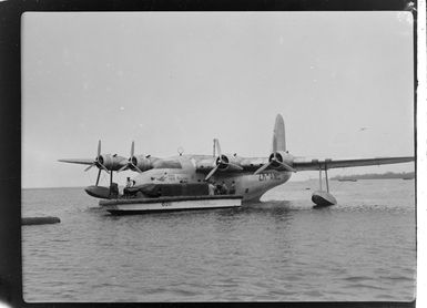 Tasman Empire Airways flying boat, RMA New Zealand ZK-AME at Lauthala Bay Suva, Fiji, includes unidentified group of men on boat with luggage