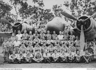 Group portrait of air and ground crew of B Flight, No. 30 Squadron RAAF, on and in front of one of the squadron’s Beaufighter aircraft at Ward’s Strip. Back row, left to right (seated on the ..