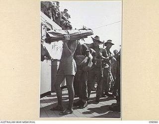 WEWAK HARBOUR, NEW GUINEA. 1945-11-25. TROOPS OF 6 DIVISION, OUTSIDE A HATCHWAY ON HMAS SHROPSHIRE, BEING DIRECTED TO THEIR BUNKS BY NAVAL PERSONNEL. THE TROOPS ARE RETURNING TO AUSTRALIA FOR ..