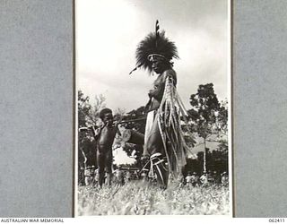 17 MILE, PORT MORESBY AREA, PAPUA, NEW GUINEA. 1943-12-25. A LOCAL NATIVE DRESSED IN BIRD OF PARADISE FEATHERS WAITING HIS TURN TO DANCE DURING THE 10TH AUSTRALIAN ADVANCED ORDNANCE DEPOT SPORTS ..