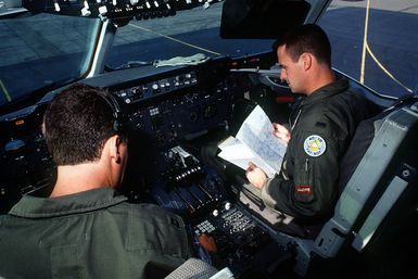 CAPT. Richard Berger, left, aircraft commander, and 1ST LT. Mike Mathews perform a preflight inspection in the cockpit of a KC-10A Extender aircraft during a Military Airlift Command channel cargo mission. Both are with the 6th Air Refueling Squadron, 22nd Air Refueling Wing