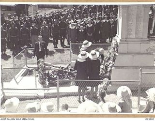 HERBERTON, QLD. 1944-04-25. WREATHS BEING LAID AT THE BASE OF THE WAR MEMORIAL BY FIRST WORLD WAR VETERANS AND PUPILS OF ST. MARY'S SCHOOL. THE SHIRE CLERK OF HERBERTON, MR STOBLE, WAS IN CHARGE OF ..