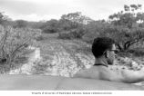 Richard Billings riding on the bumper of a jeep used for research on Enjebi Island, summer 1964