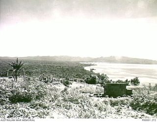 THE SOLOMON ISLANDS, 1945-10-15. VIEW OF THE COASTLINE OF BOUGAINVILLE ISLAND WITH SOME JAPANESE FORTIFICATIONS IN THE FOREGROUND AND A BEACHED SHIP IN THE MIDDLE DISTANCE. (RNZAF OFFICIAL ..