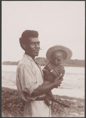 Ni-Vanuatu man holding a baby at Mota Lava beach, Banks Islands, 1906 / J.W. Beattie