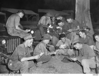 RABAUL, NEW BRITAIN. 1945-10-27. TROOPS OF A COMPANY, 26 INFANTRY BATTALION, READING THEIR MAIL BY JEEP LIGHT. THEY WERE MARCHED FROM THEIR UNIT AREA TO BIVOUAC FOR THE NIGHT NEAR THE PARADE GROUND ..