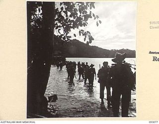 WATU POINT, OPEN BAY, NEW BRITAIN, 1945-05. TROOPS OF B COMPANY, 37/52 INFANTRY BATTALION, WADING ASHORE FROM BARGES, AS THEY ARRIVE AT THEIR NEW CAMP SITE TO RELIEVE 36 INFANTRY BATTALION. THE MEN ..