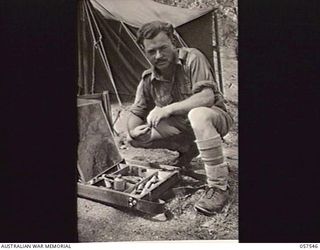 NEW GUINEA. 1943-07-25. SERGEANT C. BUSH, AUSTRALIAN WAR ARTIST, HEADQUARTERS, NEW GUINEA FORCE WITH HIS BOX OF PAINTS
