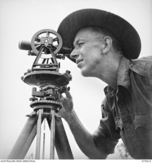 MARKHAM VALLEY, NEW GUINEA. 1944-08-28. VX74093 BOMBARDIER T.J.C. HOLTZ OF THE SURVEY SECTION, 4TH FIELD REGIMENT, USING A THEODOLITE WHILE SURVEYING A NEW AREA NEAR THE CAMP