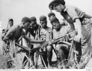 New Guinea. 1943. Members of a Papuan Infantry Unit prior to a forward area patrol. Sergeant F. Wust of Eumundi, Qld, checks his patrol's weapons