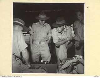 NADZAB, NEW GUINEA. 1944-10-21. NX179 COLONEL E.A. COLEMAN (1), WITH VX39135 MAJOR A.K. GOUCH (2), EXAMINE AN UNDAMAGED WIRELESS TRANSMITTER SUCCESSFULLY DROPPED BY PARACHUTE DURING TESTS CONDUCTED ..