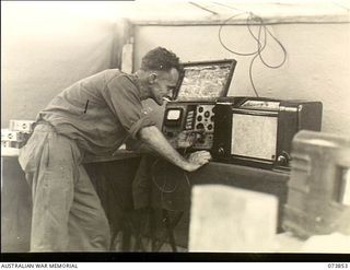 Madang, New Guinea. 1944-06-14. QX59075 Craftsman E. O. Ross, Wireless Mechanic, 266th Light Aid Detachment, Headquarters 15th Infantry Brigade, at work. The unit is located in Siar Plantation