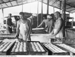 DUMPU, RAMU VALLEY. 1943-11-20. BAKERS OF NO. 2 SECTION, NO. 3 PLATOON, 4TH AUSTRALIAN FIELD BAKERY, PREPARING TO BAKE A BATCH OF BREAD ROLLS FOR THE TROOPS