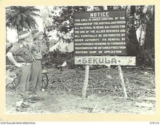 SEKULA, NEW GUINEA. 1944-07-30. OFFICERS OF THE 8TH INFANTRY BRIGADE READING A NOTICE ON THE BEACH AT THE 5TH DIVISION SALVAGE DUMP. THEY ARE:- NX112703 CAPTAIN O. HEWISON-COOPER, 30TH INFANTRY ..