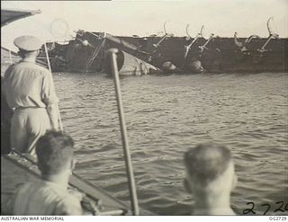 PORT MORESBY, PAPUA. C. 1944. CREW MEMBERS OF A MOTOR LAUNCH OF THE RAAF RESCUE SERVICE LOOK AT THE WRECK OF THE MV MACDHUI WHICH WAS THE TARGET OF ATTACKS BY JAPANESE BOMBER AIRCRAFT ON ..