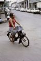 French Polynesia, woman riding motorized bicycle in Papeete