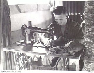 MADANG, NEW GUINEA. 1944-08-15. NX152192 SERGEANT A.G.H. CUNNINGHAM, TAILOR, 165TH GENERAL TRANSPORT COMPANY, REPAIRING ARTICLES OF CLOTHING IN THE UNIT TAILOR'S SHOP