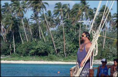 Man in blue singlet standing on boat