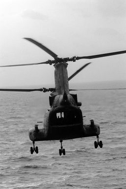 A CH-46 Sea Knight helicopter takes off from the amphibious assault ship USS GUAM (LPH 9) during Operation URGENT FURY