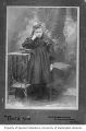 Young unidentified girl posed next to table with two books, Seattle, Washington, approximately 1897