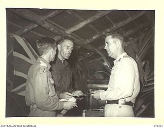 KALUMALAGI RIVER, NEW BRITAIN. 1945-02-24. NX54553 LIEUTENANT R.A. WITNEY (1); CORPORAL A. JOHNSTON (2) AND SALVATION ARMY COMMANDER, W.J. JOHNS (3) PREPARING THE MUSICAL PROGRAMME FOR THE OFFICIAL ..