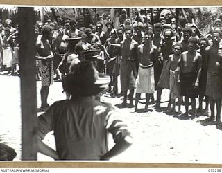 HOPOI, NEW GUINEA, 1943-10-20. NX155085 CAPTAIN R.G. ORMSBY OF THE AUSTRALIAN AND NEW GUINEA ADMINISTRATIVE UNIT ADDRESSING THE VILLAGE NATIVES IN A TALK ON THE WAR AND APPEALING FOR THEIR ..