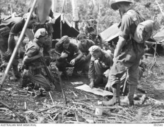 BOUGAINVILLE. 1945-05-24. LIEUTENANT D.F. CHAPLAIN, D COMPANY, 26 INFANTRY BATTALION (AUSTRALIAN IMPERIAL FORCE) (1), BRIEFING HIS PATROL AND EXPLAINING ENEMY MOVEMENTS BEFORE LEAVING THE COMPANY ..