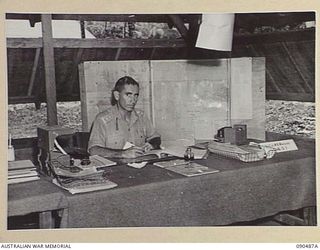 JACQUINOT BAY, NEW BRITAIN. 1945-04-11. LIEUTENANT COLONEL W.B. MAGUIRE WORKING IN HIS OFFICE AT HEADQUARTERS 5 DIVISION