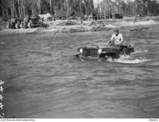 SOUTH BOUGAINVILLE. 1945-07-24. PRIVATE R.A. TUMNEY, 58/59 INFANTRY BATTALION, 15 INFANTRY BRIGADE, FINDING IT HARD TO KEEP A DRY SEAT IN HIS JEEP WHILE ATTEMPTING TO CROSS THE FLOODED MOBIAI RIVER ..