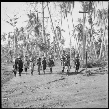 Ten women carrying bags on their heads walking to the Boong, native markets, Rabaul, New Guinea, ca. 1936, 2 / Sarah Chinnery