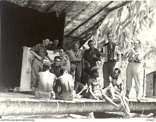MILILAT, NEW GUINEA. 1944-08-23. NEW GUINEA NATIVES FORM A KNOT OF INTERESTED SPECTATORS DURING A REHEARSAL BY THE "TASMANIACS", THE TASMANIAN LINES OF COMMUNICATION CONCERT PARTY. IDENTIFIED ..