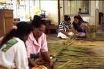 Adult education class instructor passing on weaving skills to younger women